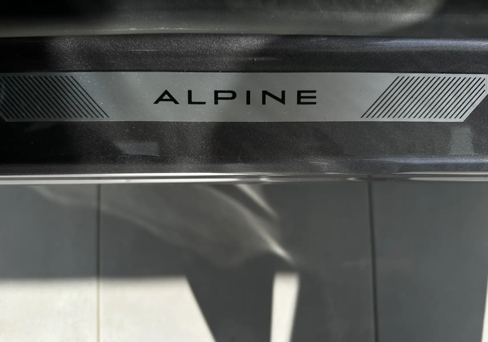 Plaque de seuil de porte avec inscription Alpine sur Renault Symbioz Esprit Alpine gris Cassiopée, détail intérieur.