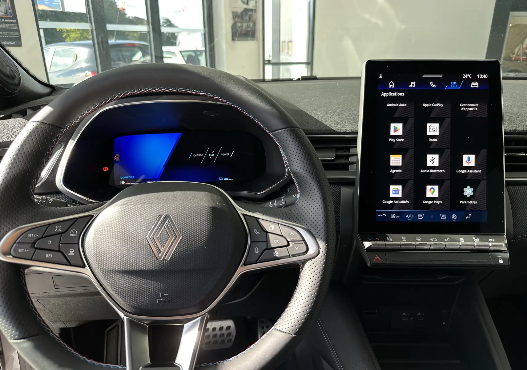 Vue intérieure centrée sur le volant cuir noir avec logo Renault et écran tactile vertical du tableau de bord.