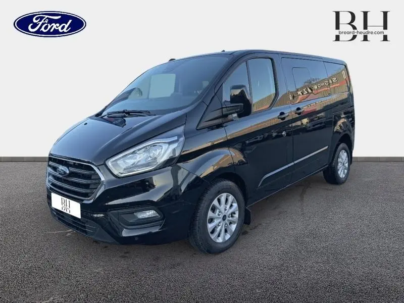 Ford Transit Custom Fourgon noir Agate métallisé, vue 3/4 avant droit avec calandre chromée et jantes alu 16 pouces.