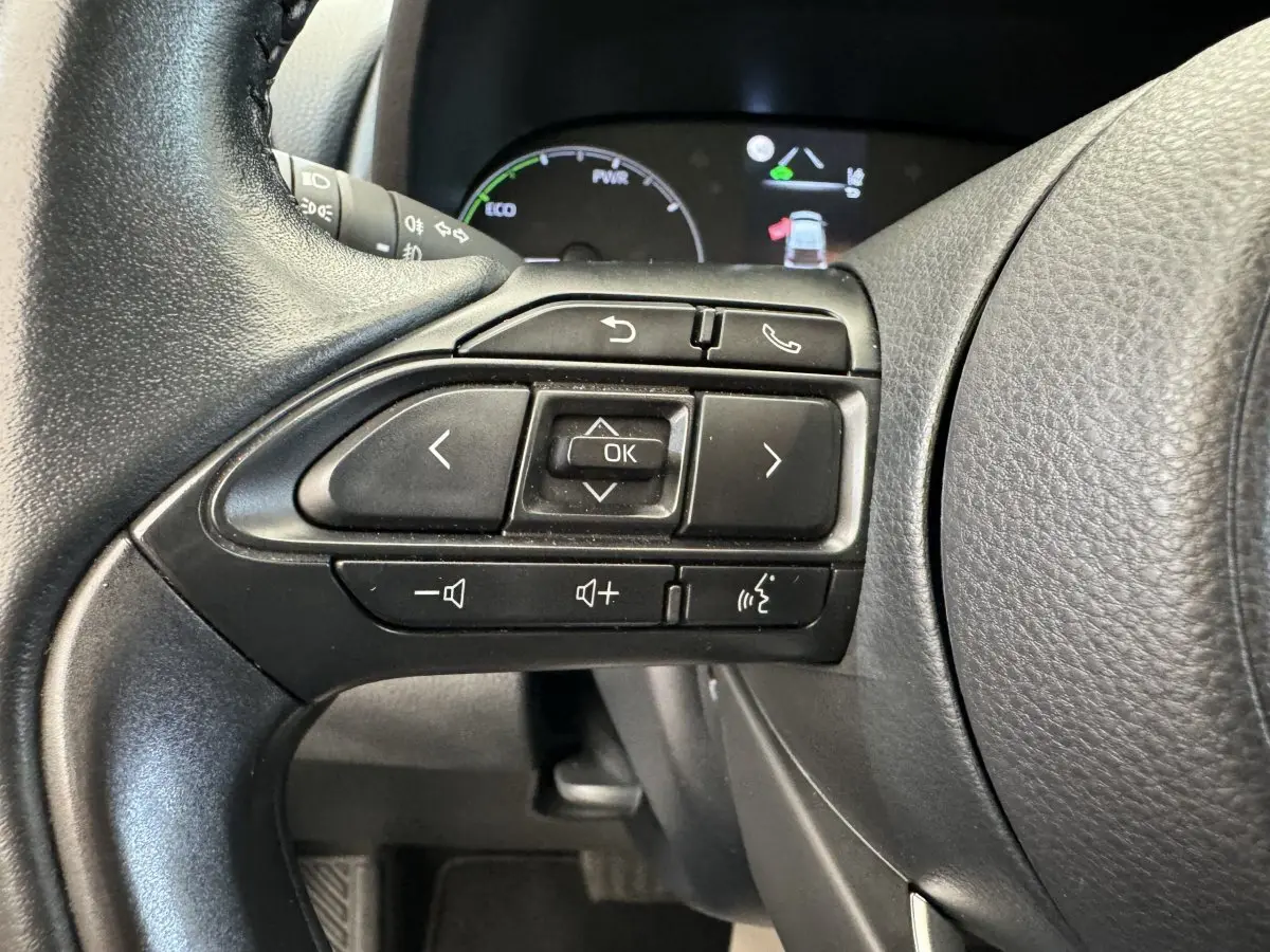 Gros plan sur les commandes multifonctions noires du volant côté gauche de la Toyota Yaris hybride 2022.