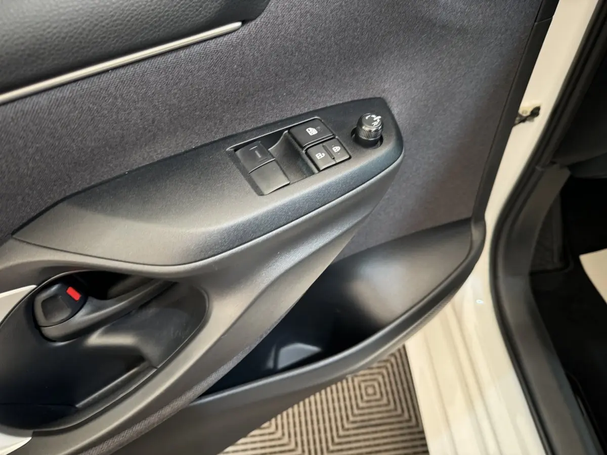 Gros plan sur la porte avant gauche blanche de la Toyota Yaris hybride 2022, montrant les commandes des vitres et le verrouillage.