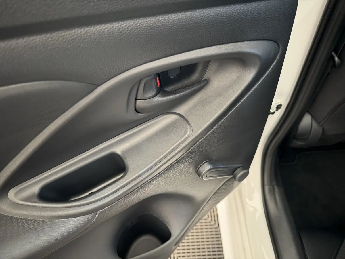 Gros plan sur la porte arrière droite intérieure noire d'une Toyota Yaris blanche hybride 2022, avec manivelle de vitre.