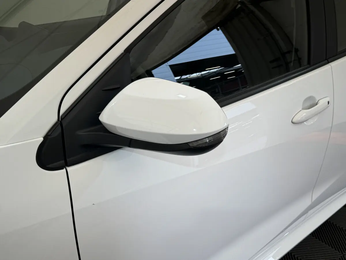 Gros plan sur le rétroviseur côté gauche blanc de la Toyota Yaris hybride 2022, avec poignée de porte assortie visible.