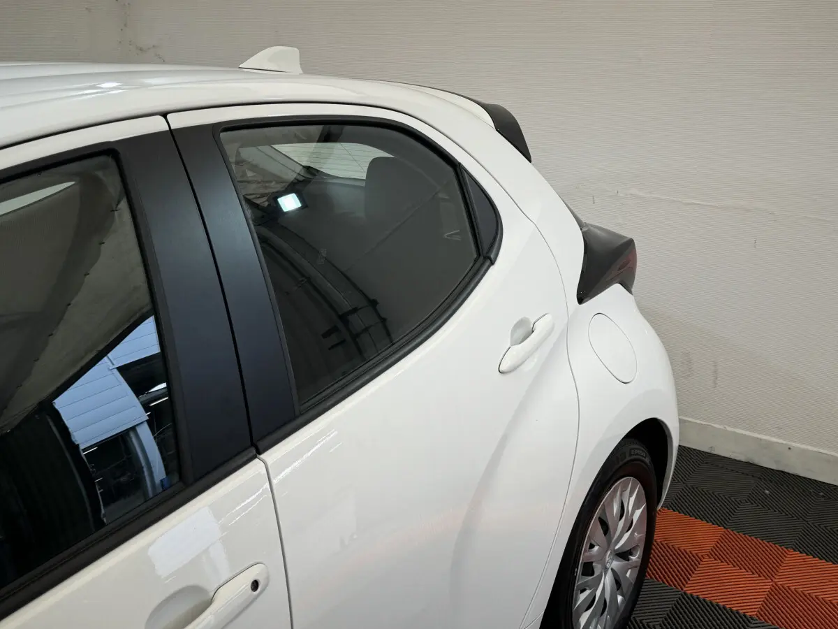 Vue côté arrière droit de la Toyota Yaris hybride blanche 2022 avec poignées et jantes visibles.