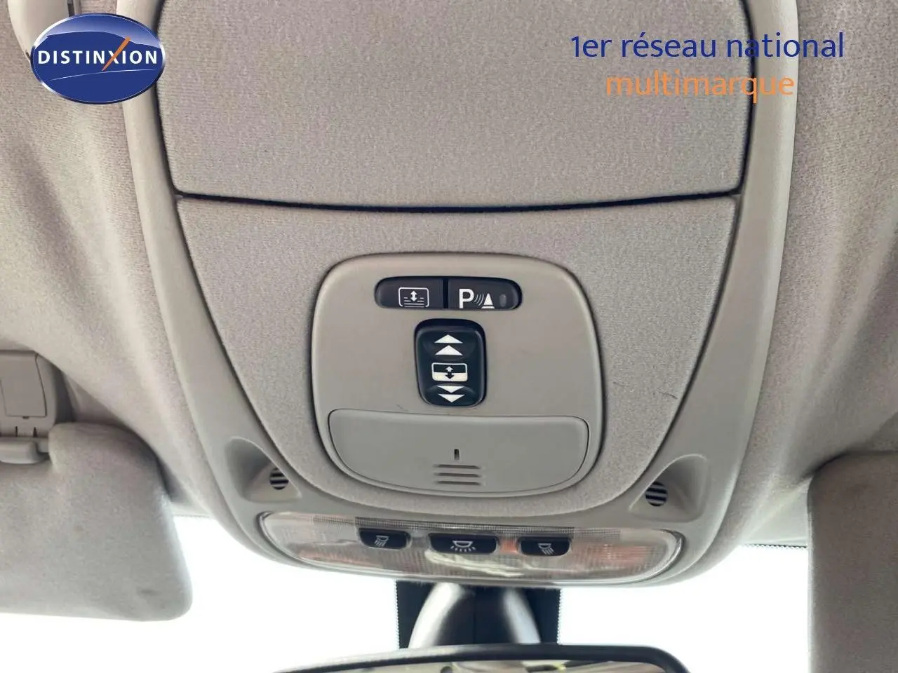 Vue intérieure en gros plan du plafonnier gris avec commandes d’éclairage et capteur de stationnement d’une Jaguar XJ6 noire.