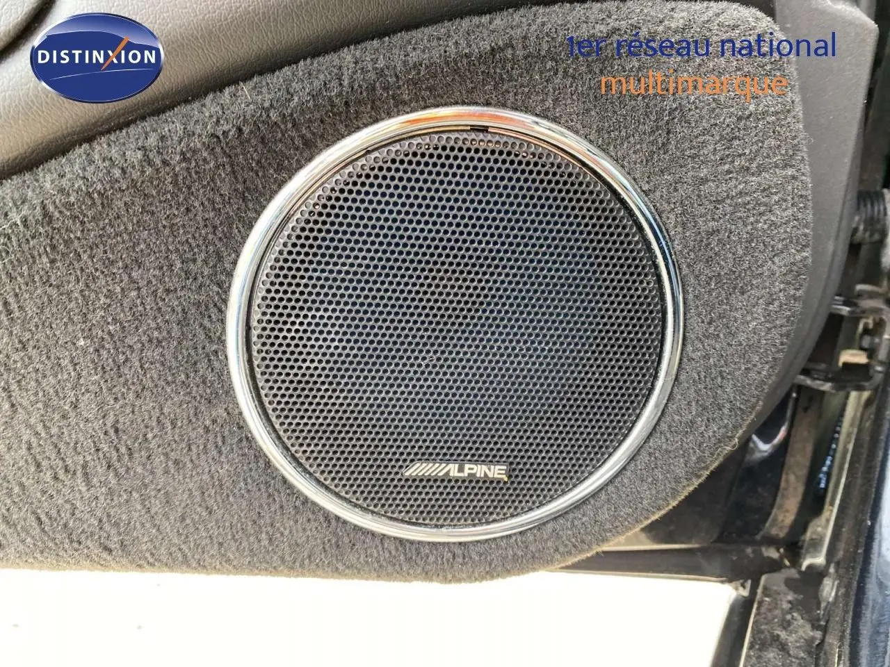 Gros plan sur l'enceinte Alpine intégrée dans la porte côté gauche d'une Jaguar XJ6 noire de 2006.