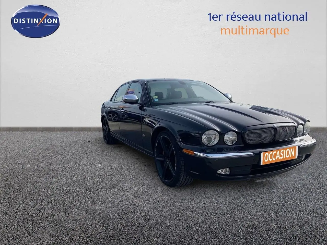 Jaguar XJ6 noir vue 3/4 avant droit, mettant en valeur ses phares ronds et ses jantes noires élégantes.