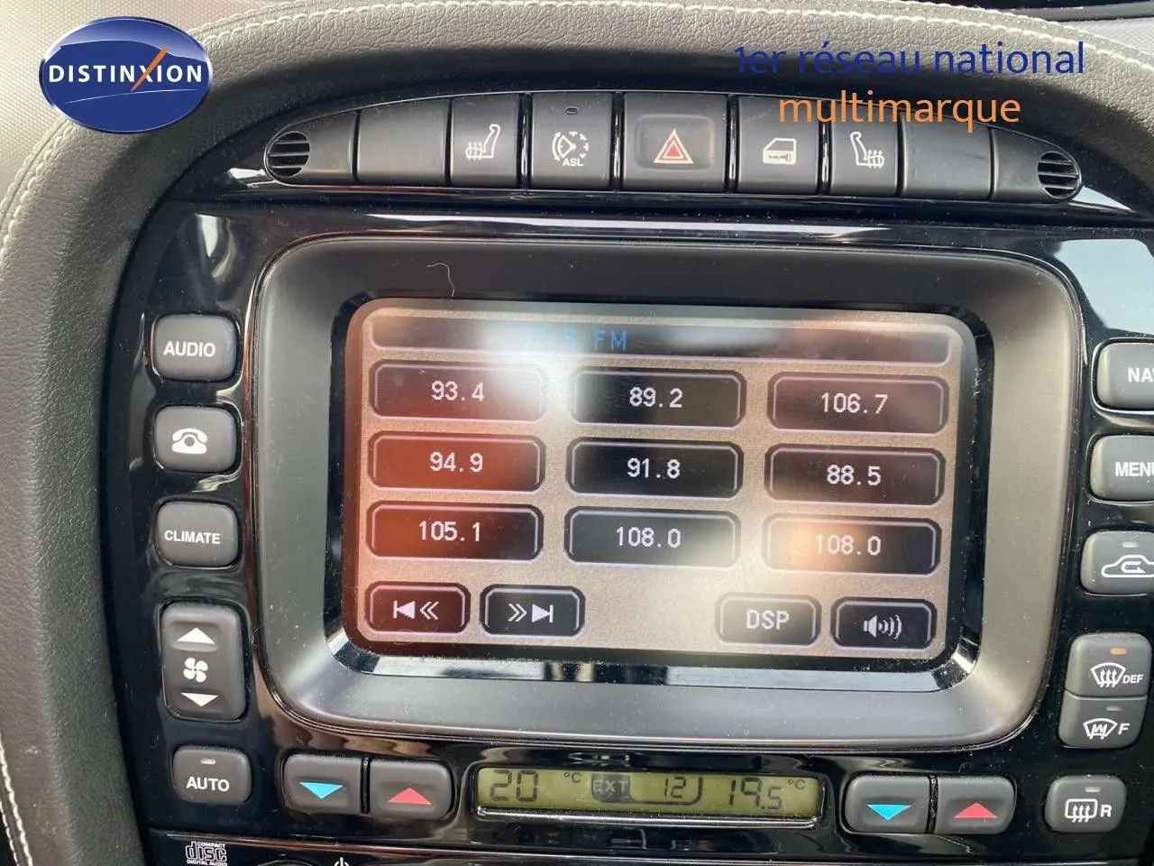 Gros plan sur l’écran central et les commandes de la Jaguar XJ6 noire de 2006, mettant en valeur la radio et la climatisation.