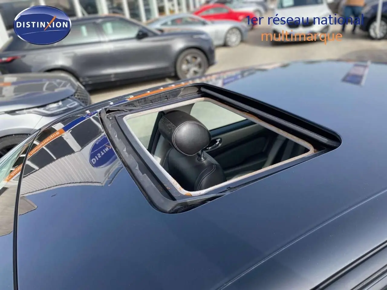 Toit ouvrant ouvert vu en plongée sur une Jaguar XJ6 noire, intérieur cuir noir visible depuis l'extérieur.