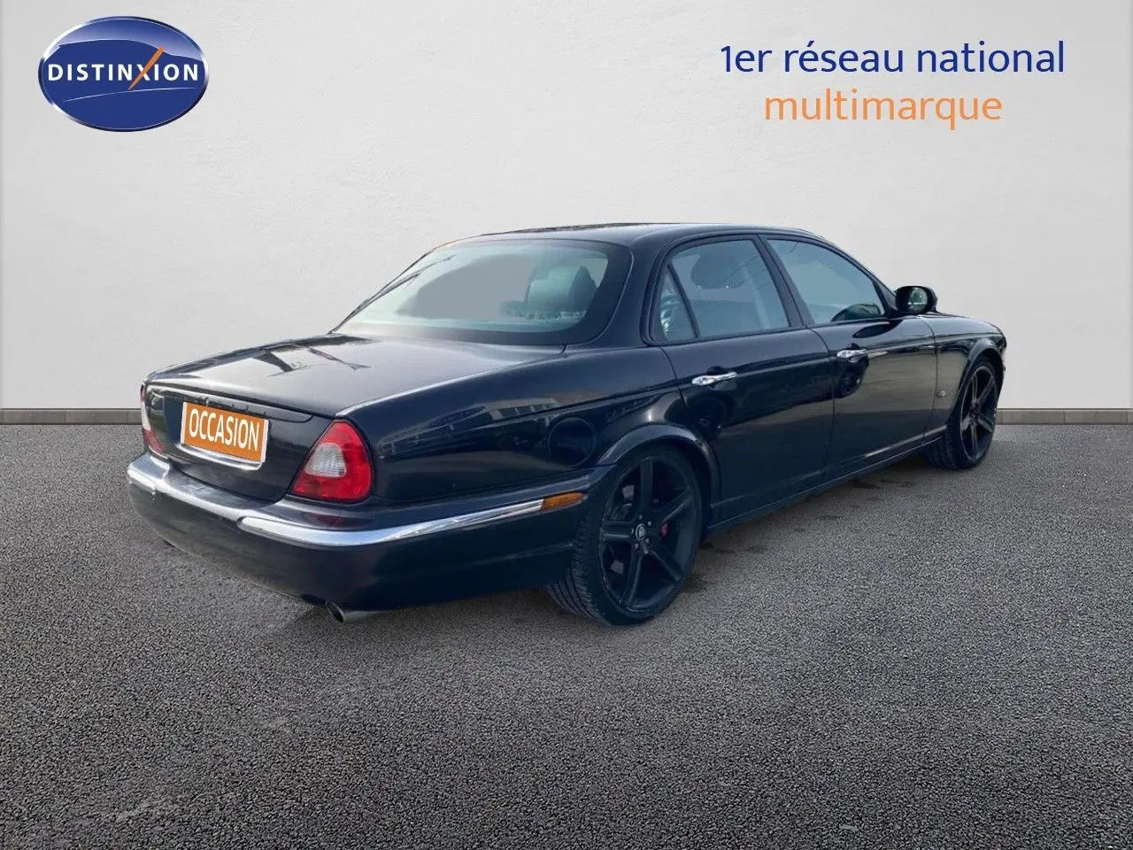 Jaguar XJ6 noir vue 3/4 arrière droit, soulignant ses jantes noires et sa silhouette élégante quatre portes.