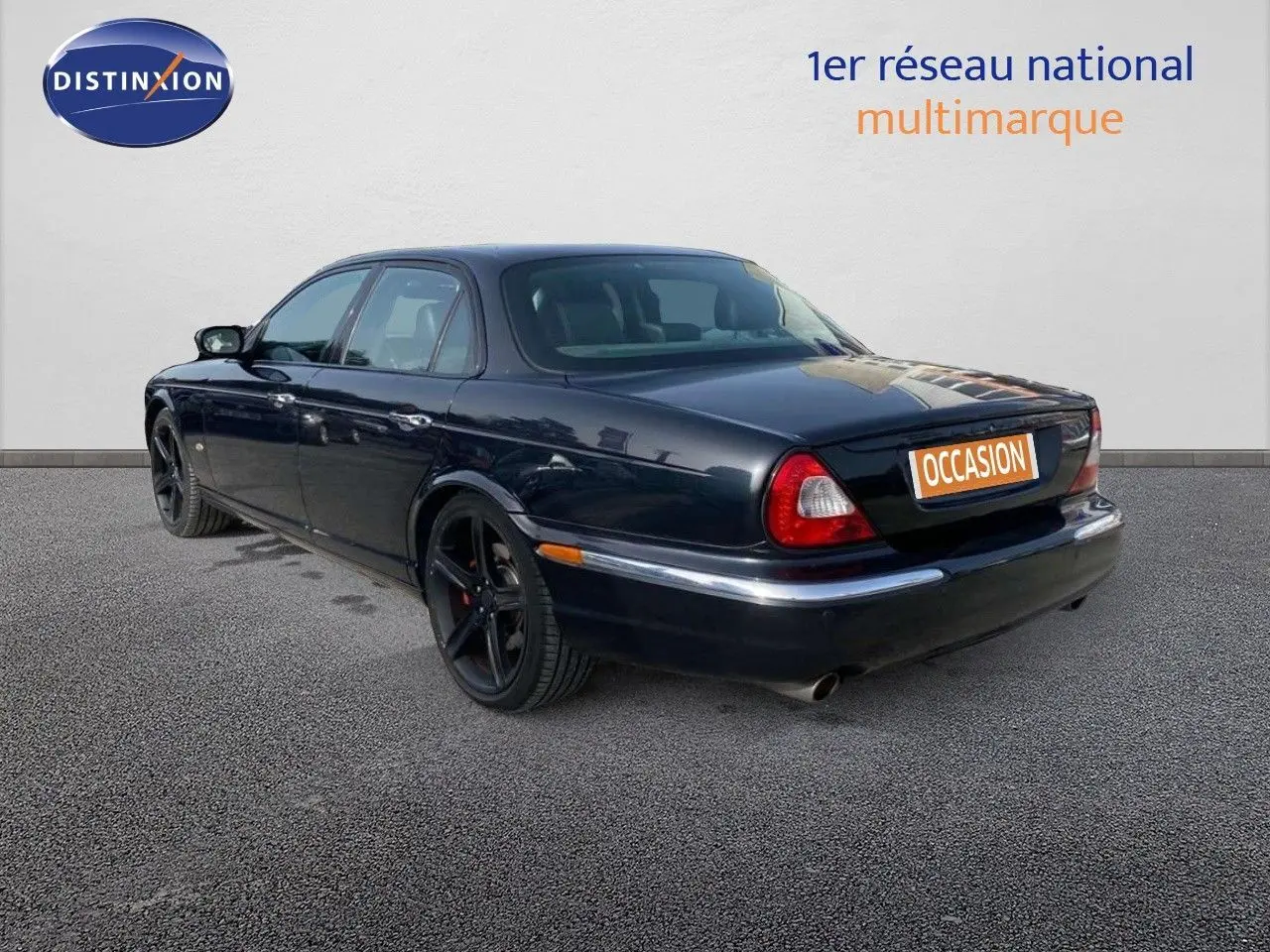 Jaguar XJ6 noir vue 3/4 arrière gauche, berline élégante avec jantes noires et feux arrière rouges.