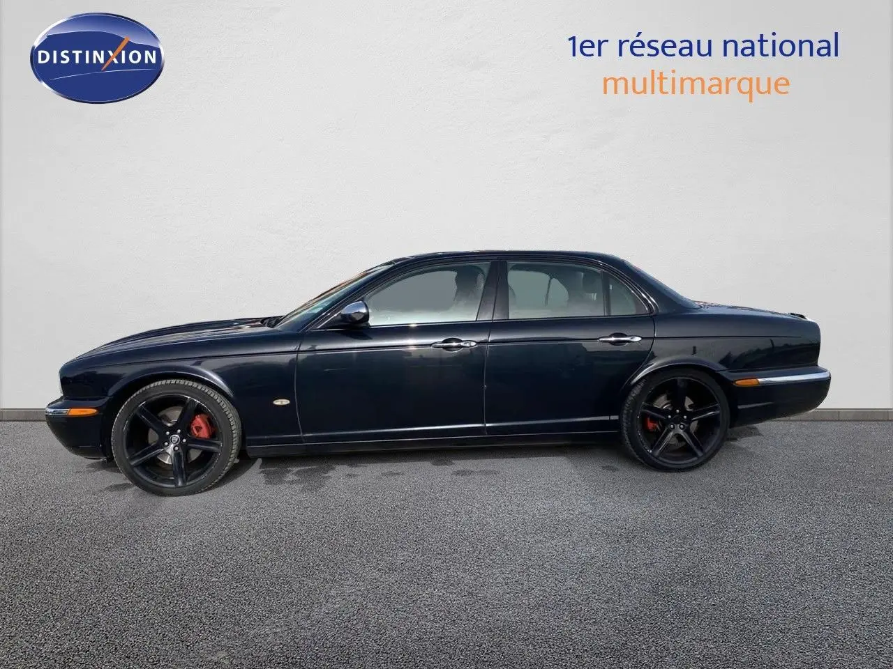Profil côté gauche d'une Jaguar XJ6 noire de 2006 avec jantes noires et étriers de frein rouges visibles.