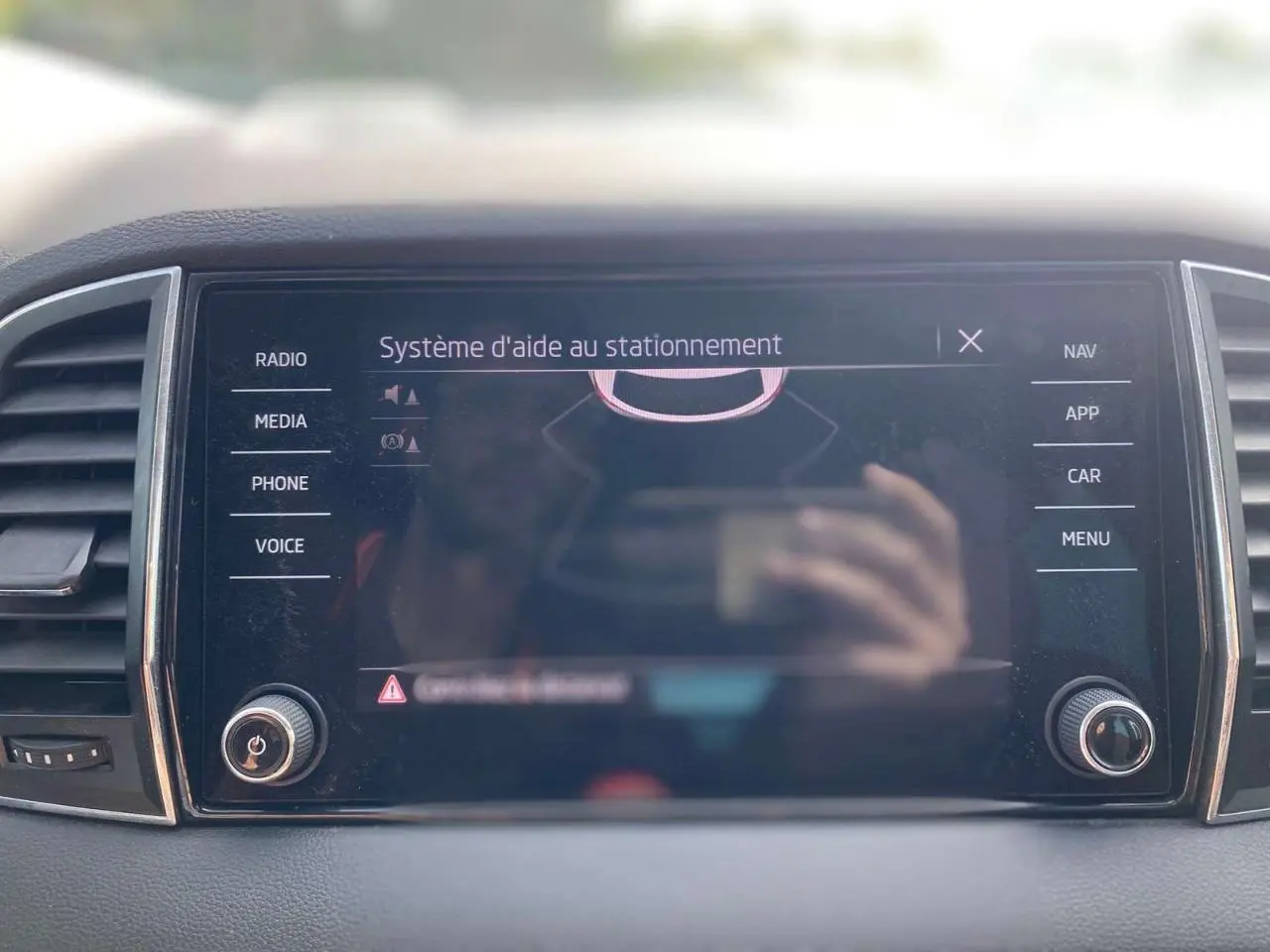Écran tactile central du tableau de bord du Skoda Karoq 2021, affichant le système d’aide au stationnement.
