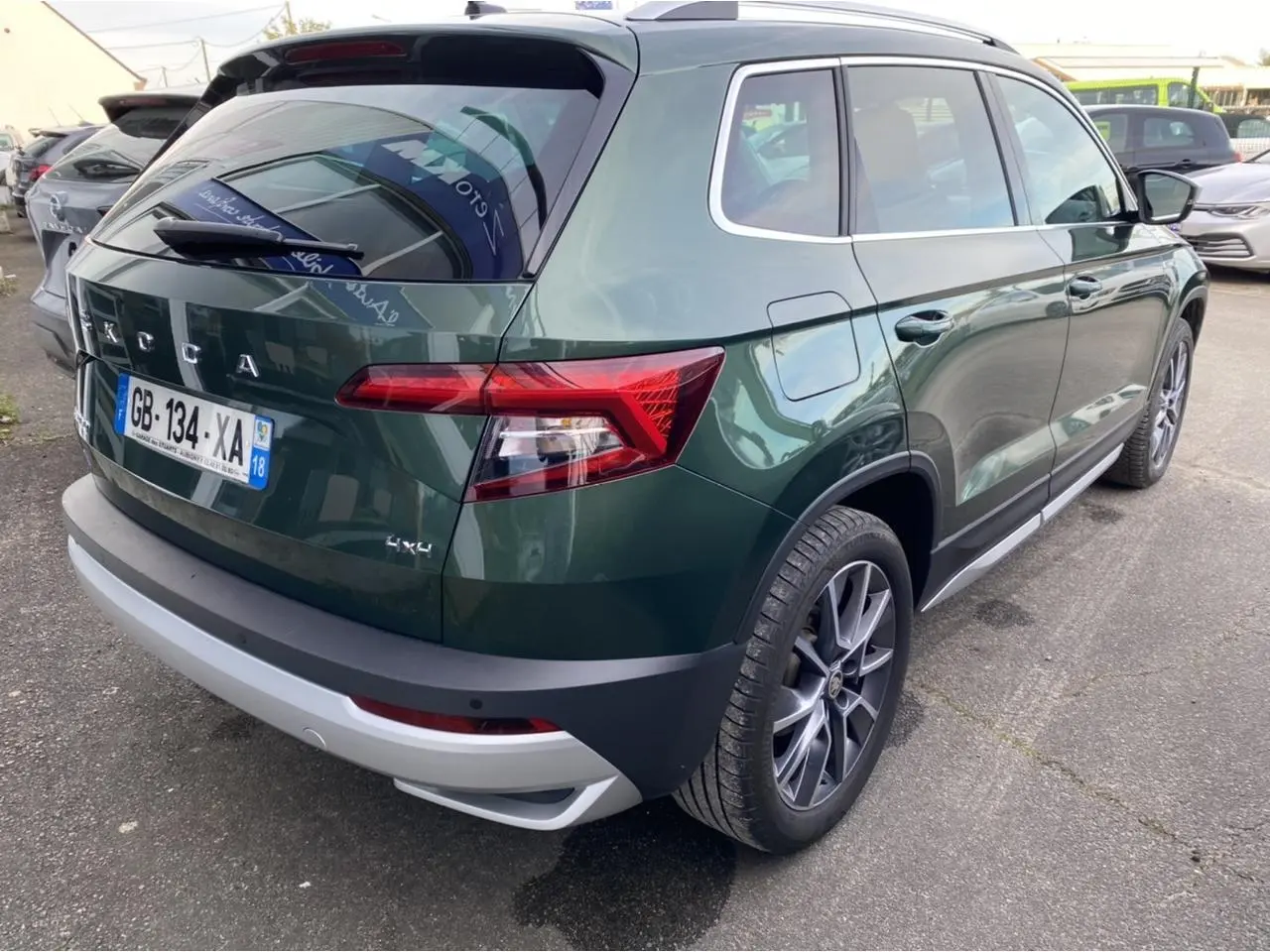 Vue 3/4 arrière droite d’un Skoda Karoq Scout vert foncé avec jantes alliage et badge 4x4 visible.