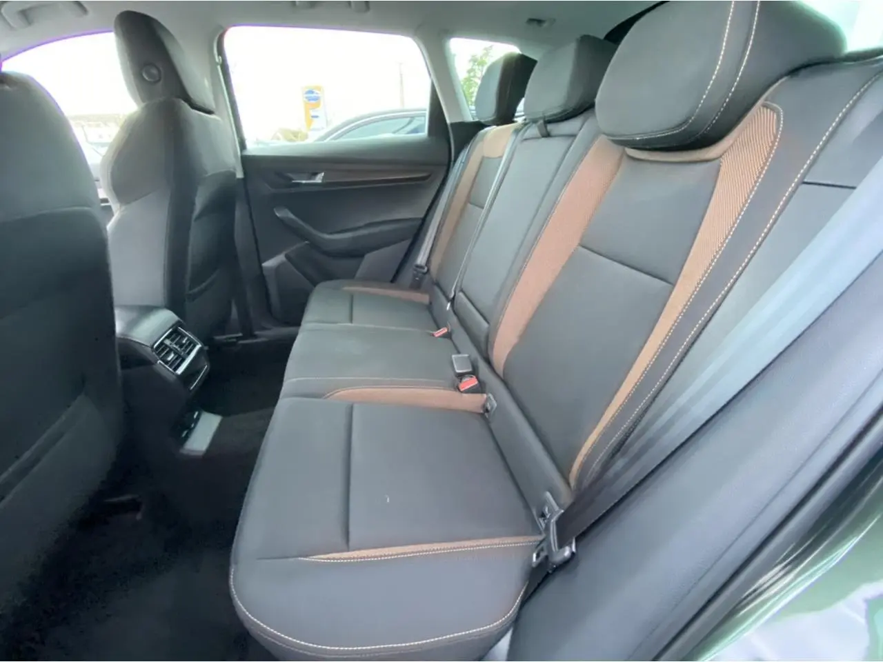 Vue intérieure côté droit des sièges arrière en cuir noir avec surpiqûres orange du Skoda Karoq Scout vert foncé 2021.