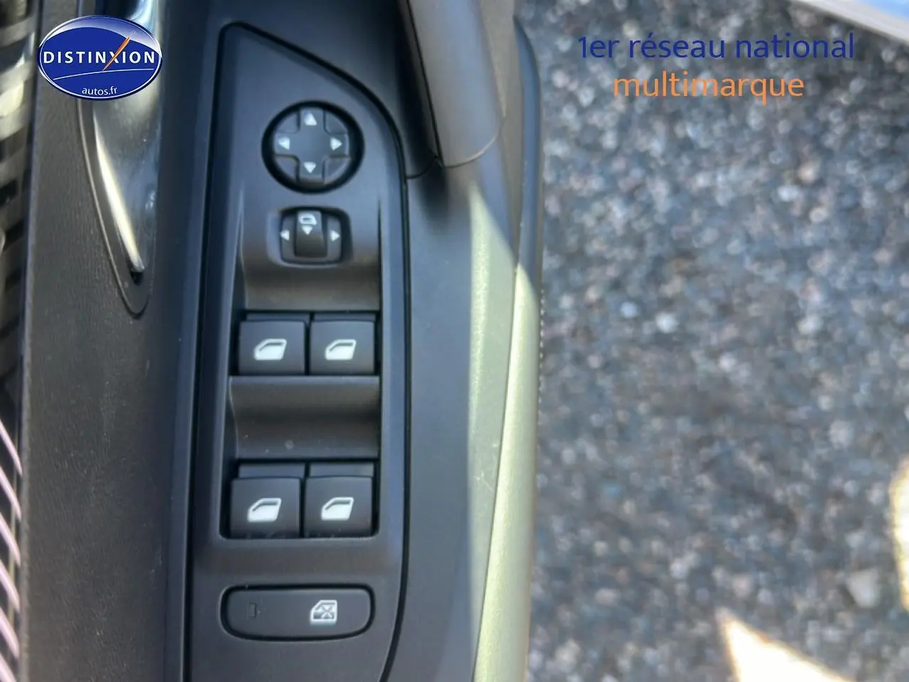 Gros plan sur les commandes de lève-vitres côté conducteur d'une Peugeot 2008 gris Artense, avec bouton de réglage des rétroviseurs.
