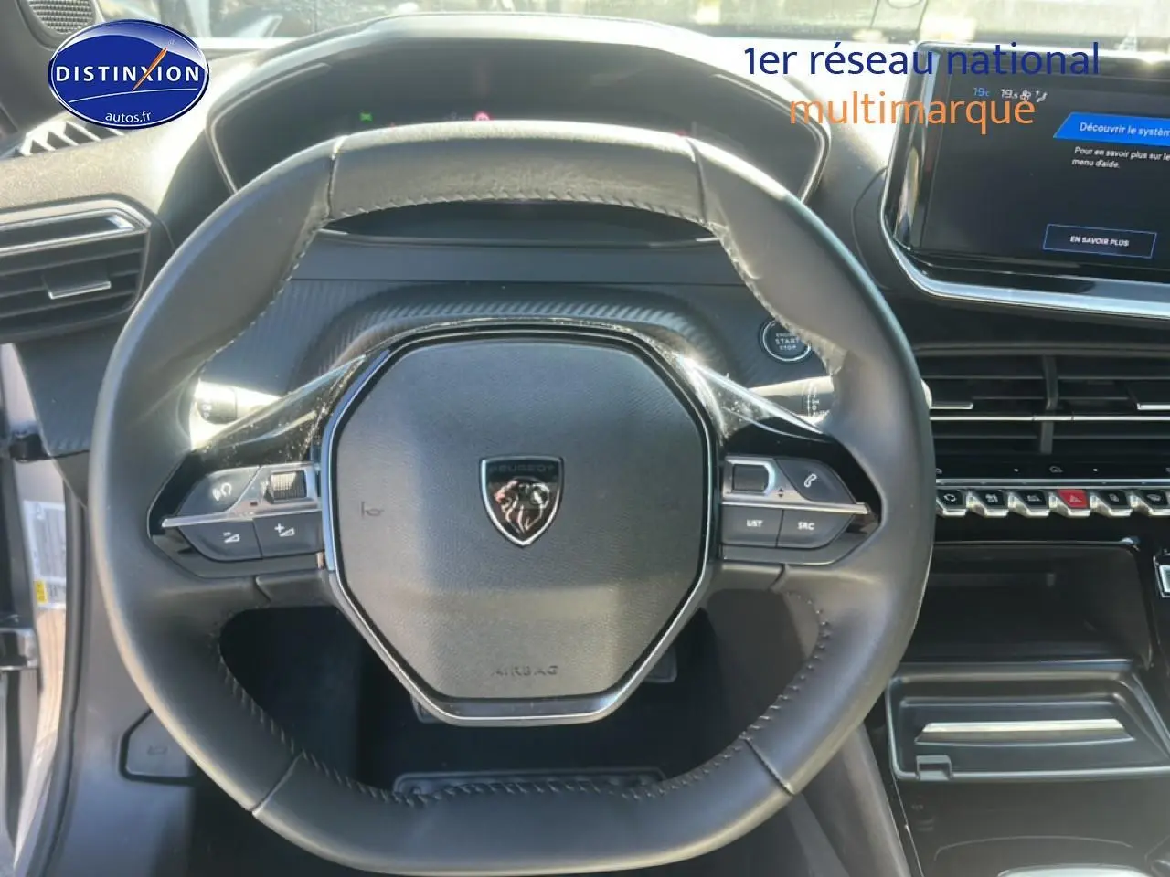 Vue rapprochée du volant multifonction noir de la Peugeot 2008 1.2 100 Allure avec tableau de bord et écran tactile visibles.
