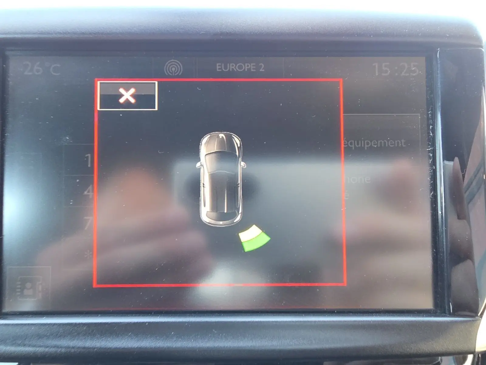 Écran central de la Peugeot 208 GTI 2015 montrant l'alerte radar de stationnement arrière avec icône voiture noire vue de dessus.