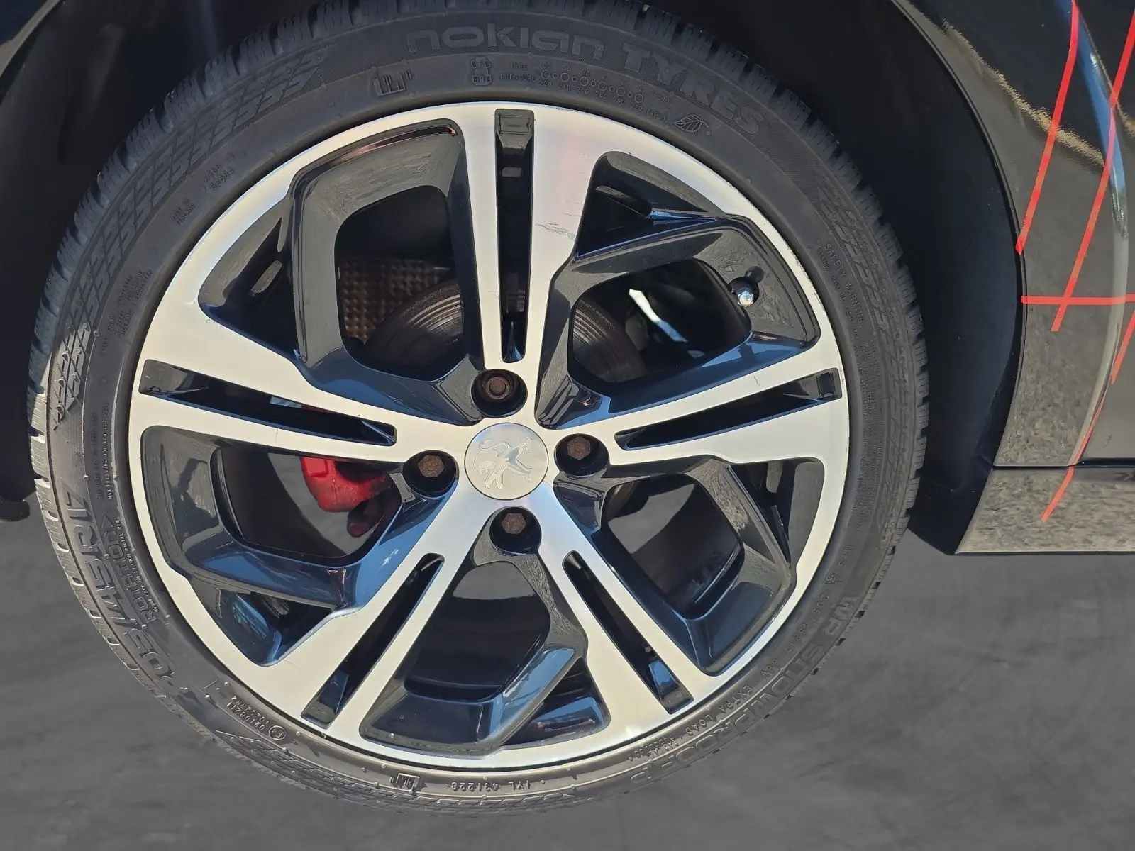 Gros plan sur la jante alliage 17” bicolore noire et argentée de la Peugeot 208 GTI noire avec étrier de frein rouge visible.