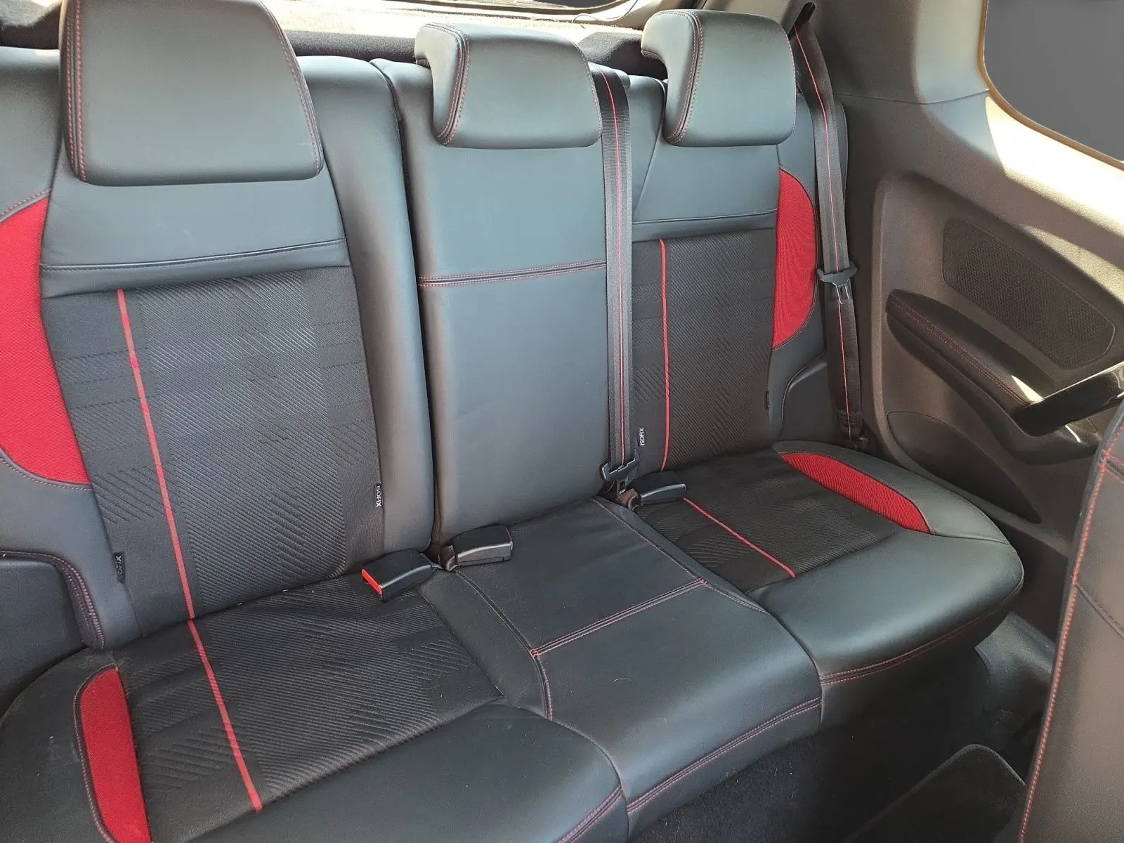 Vue intérieure arrière des sièges cuir et alcantara noirs avec surpiqûres rouges de la Peugeot 208 GTI 2015.