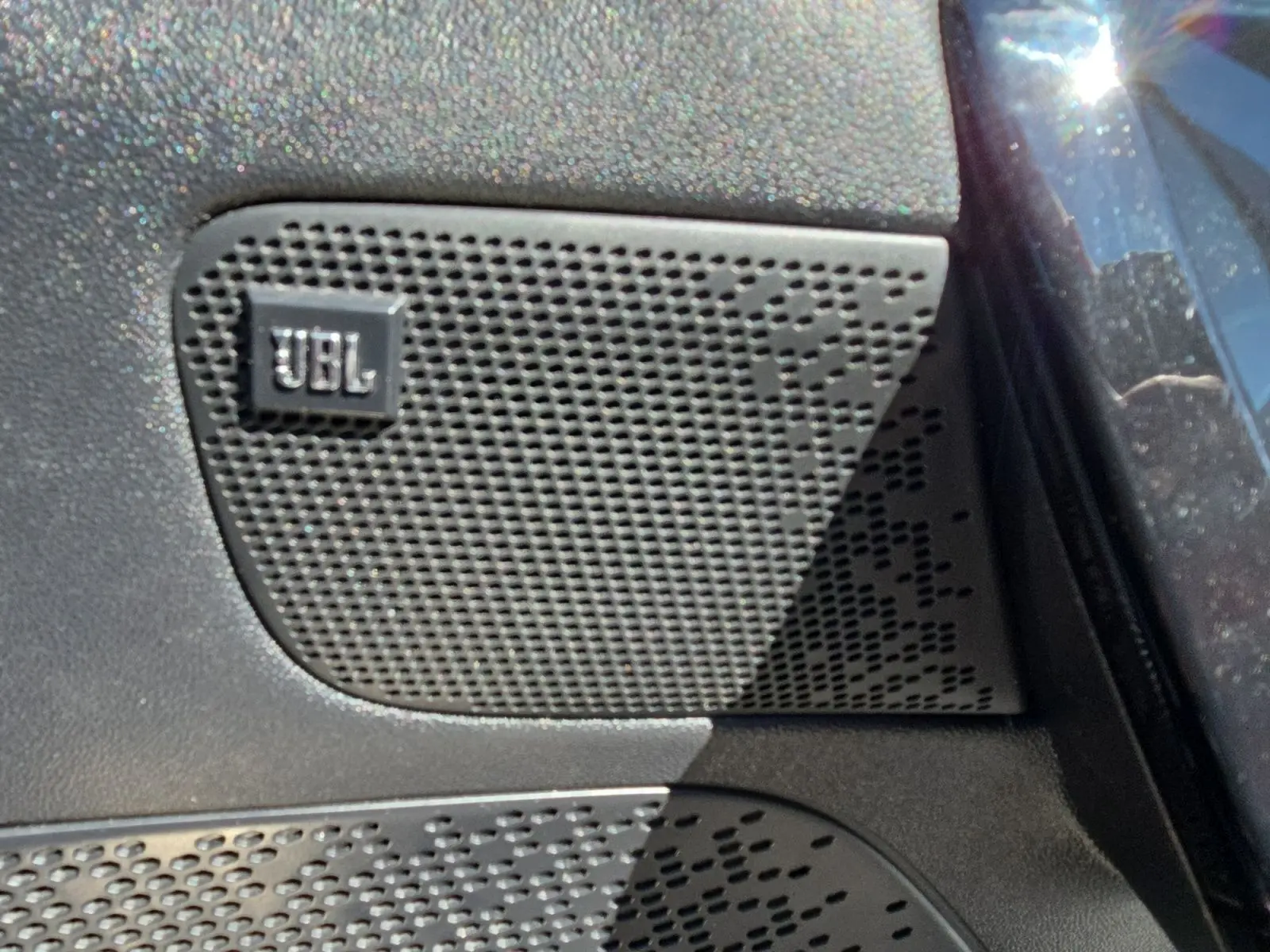Gros plan sur l'enceinte JBL intégrée à la porte côté conducteur d'une Peugeot 208 GTI noire.