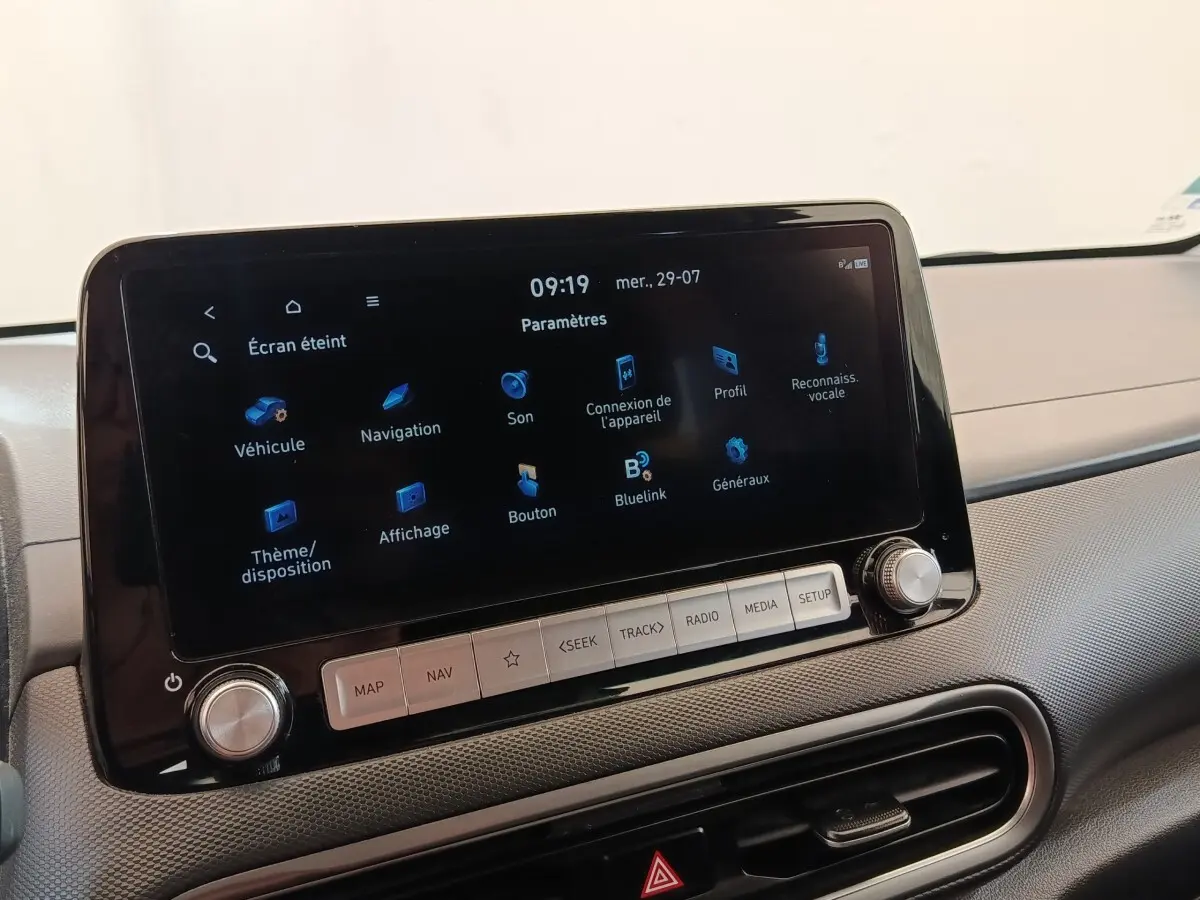 Écran tactile central allumé sur tableau de bord gris d’une Hyundai Kona électrique noire, vue intérieure avant.