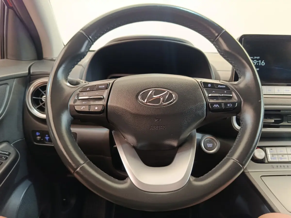 Vue rapprochée du volant cuir multifonctions d’une Hyundai Kona électrique 2023 avec tableau de bord et bouton start/stop.