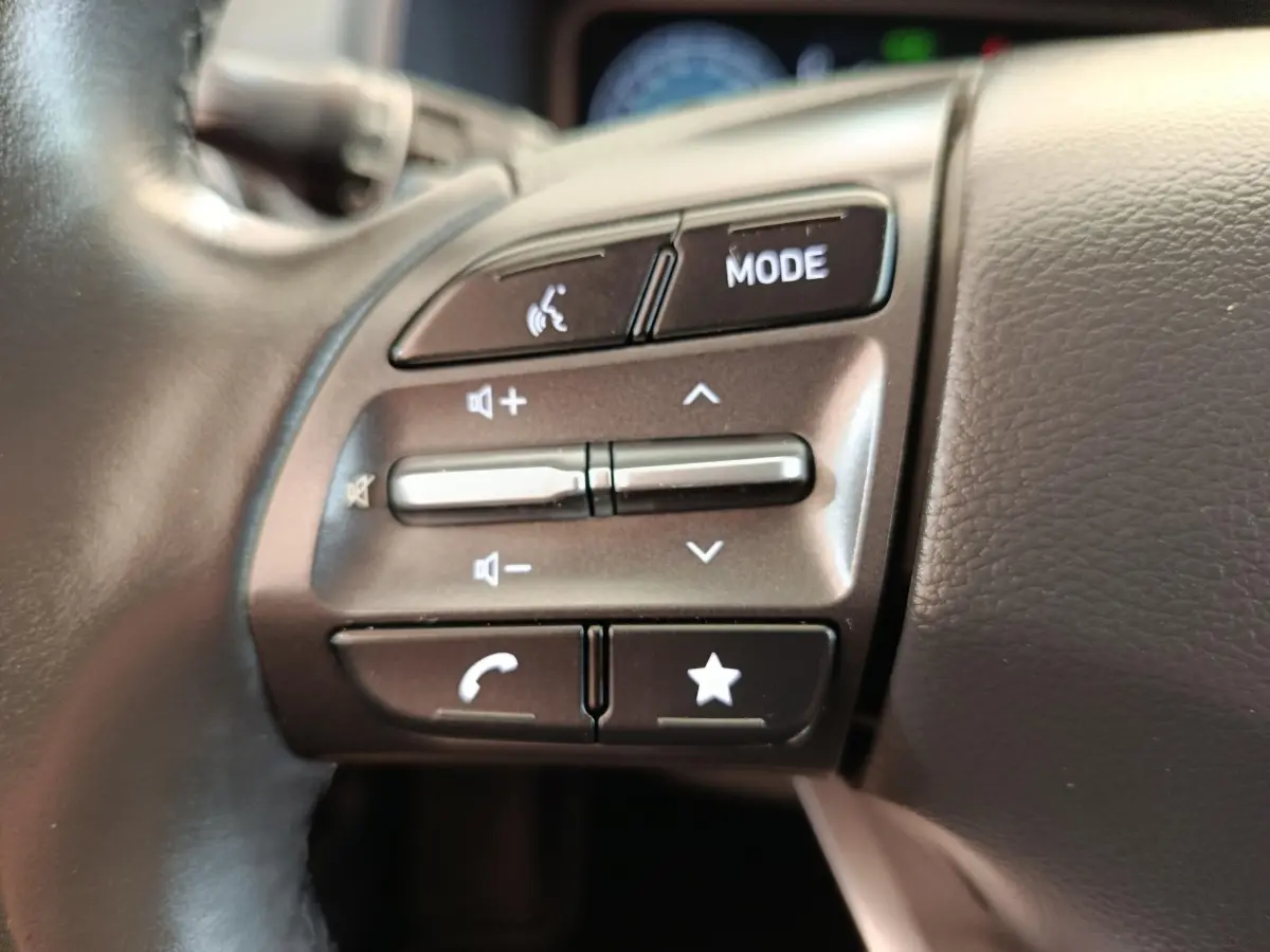 Gros plan sur les commandes du volant côté gauche du Hyundai Kona noir électrique 2023, boutons multifonctions visibles.