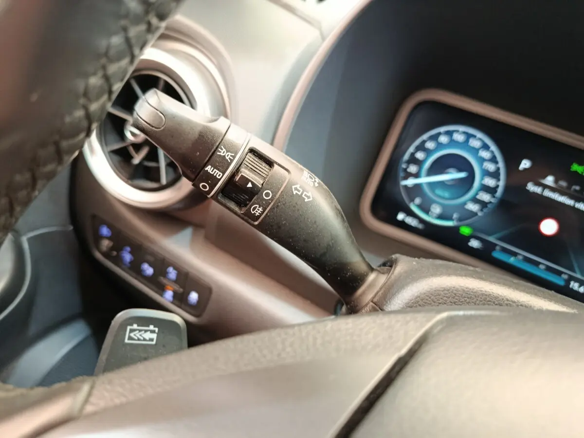 Gros plan sur la commande des feux et clignotants à gauche du volant dans l’habitacle noir du Hyundai Kona électrique 2023.
