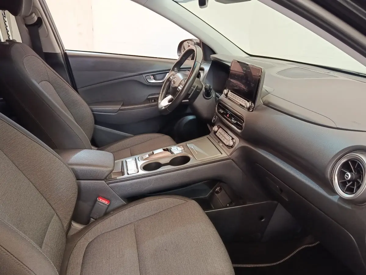 Intérieur avant droit du Hyundai Kona électrique 2023 en tissu gris avec tableau de bord et écran tactile central.