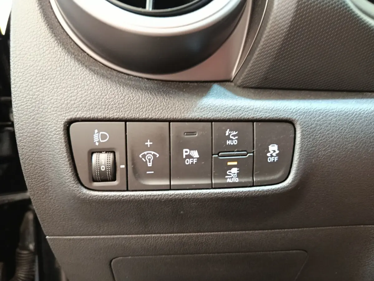 Gros plan sur les commandes de réglage des phares et aides à la conduite du tableau de bord d'une Hyundai Kona noire 2023.