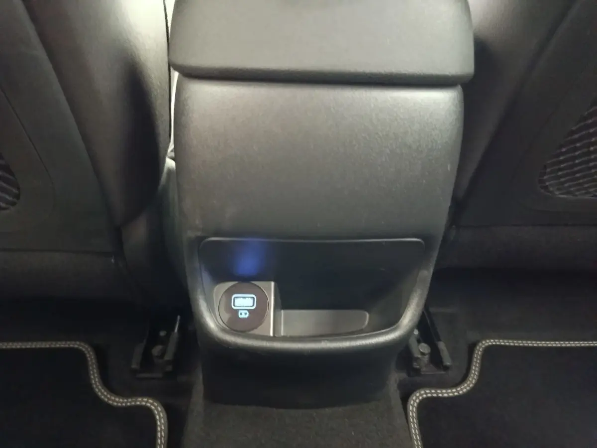 Prise USB arrière et rangement sous la console centrale du Hyundai Kona électrique noir, vue intérieure arrière.