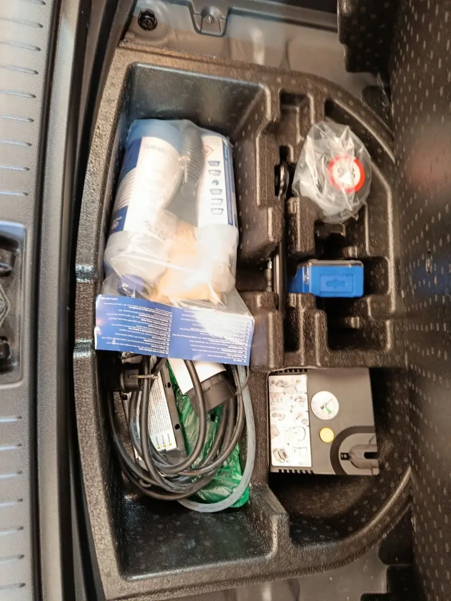 Rangement sous plancher de coffre avec câble de charge et kit de réparation sur Hyundai Kona électrique noir, vue de dessus.