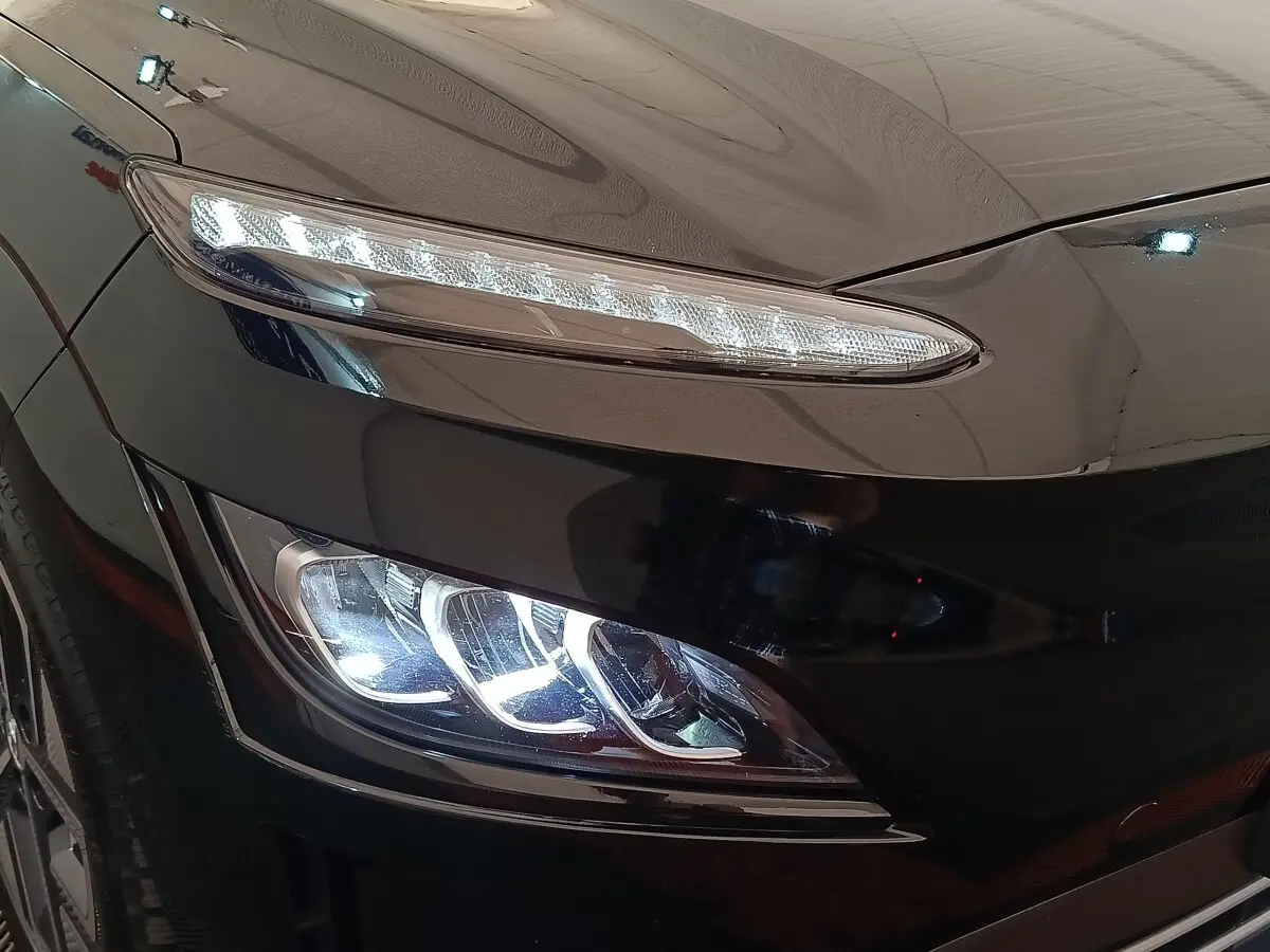Gros plan sur le phare avant gauche LED du Hyundai Kona noir électrique 2023, mettant en valeur ses lignes modernes.