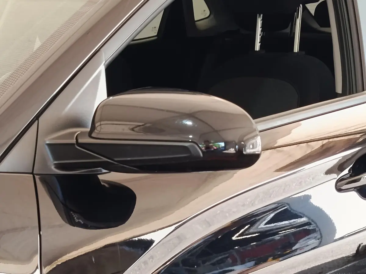 Rétroviseur côté conducteur noir brillant d'une Hyundai Kona électrique 2023, vue rapprochée du côté gauche.