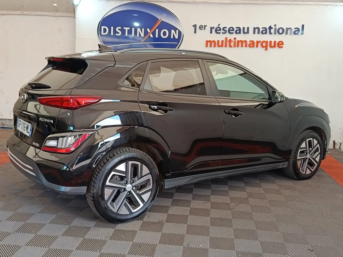 Hyundai Kona électrique noir vu de profil droit en intérieur avec jantes spécifiques et feux arrière LED.