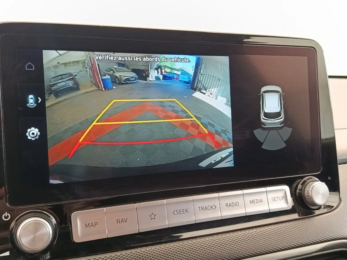 Écran tactile intérieur montrant la caméra de recul et l’aide au stationnement du Hyundai Kona noir électrique 2023.