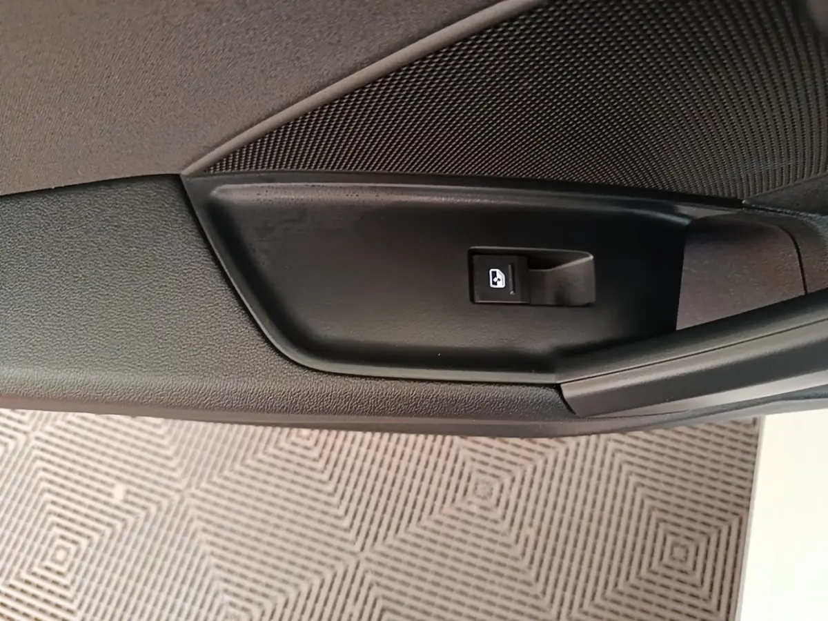 Bouton de verrouillage des portes sur la portière intérieure noire d'une Audi A3 blanche, vue en gros plan.