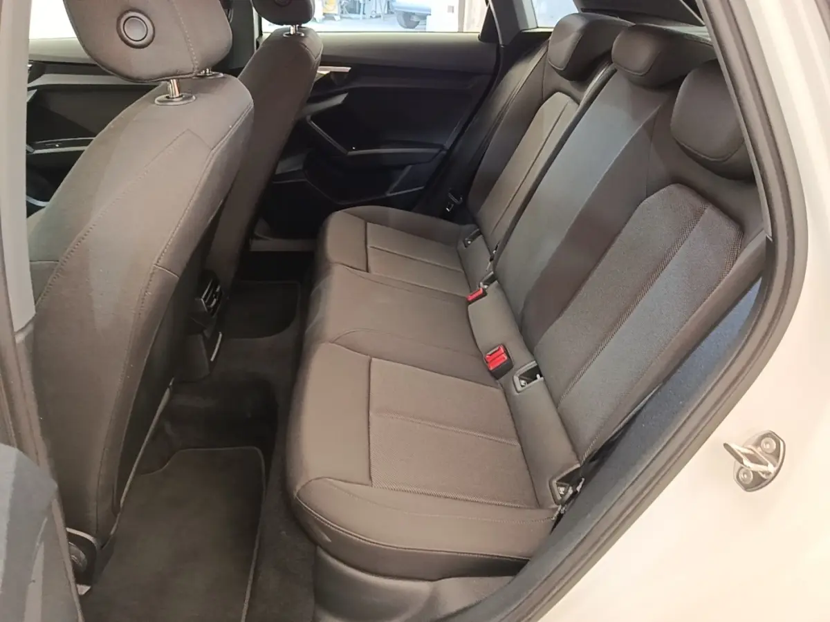 Vue intérieure côté droit sur la banquette arrière grise de l'Audi A3 40 TFSI e blanche, avec porte ouverte.