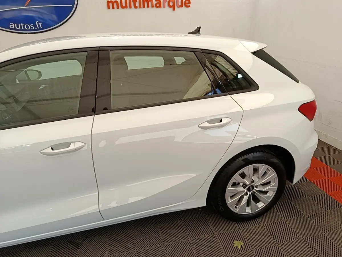 Vue latérale droite d'une Audi A3 blanche hybride rechargeable, mettant en valeur les portes arrière et la jante alliage.