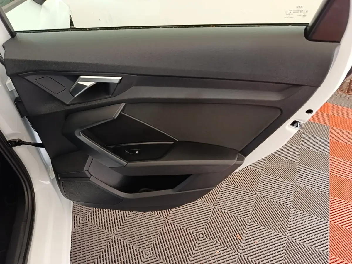 Vue rapprochée de la porte avant gauche blanche d’une Audi A3 40 TFSI e 2022 avec garniture intérieure noire.