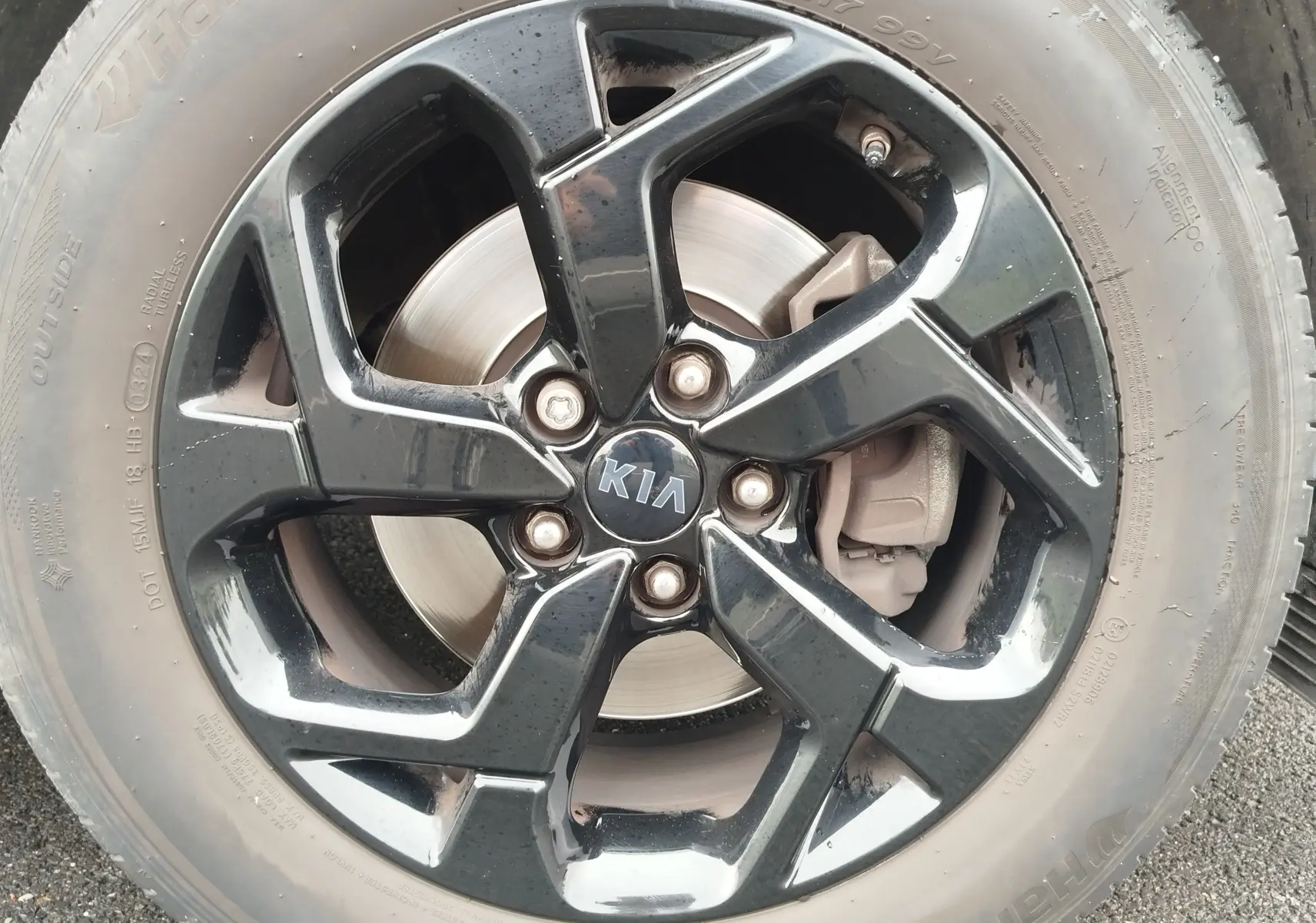 Gros plan sur la jante noire brillante d'un Kia Sportage blanc, mettant en valeur le logo central et le disque de frein.