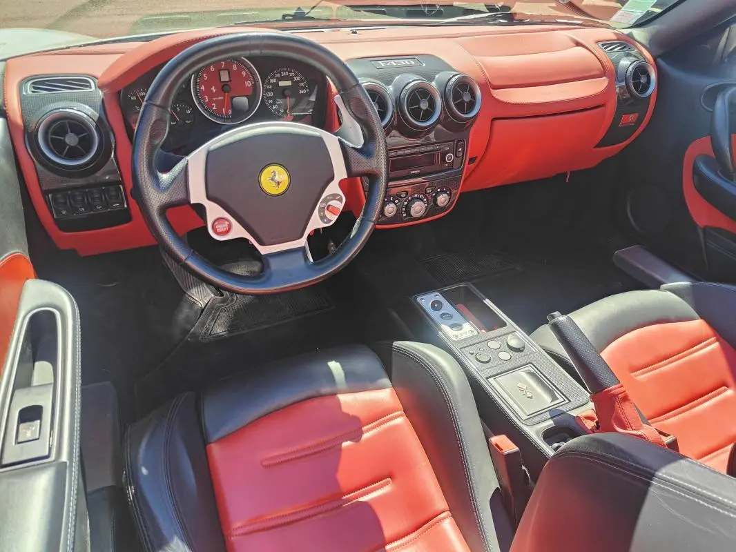 Intérieur de Ferrari F430 Spider 60ème Anniversaire 2007, vue côté conducteur, cuir rouge et noir avec tableau de bord orange.