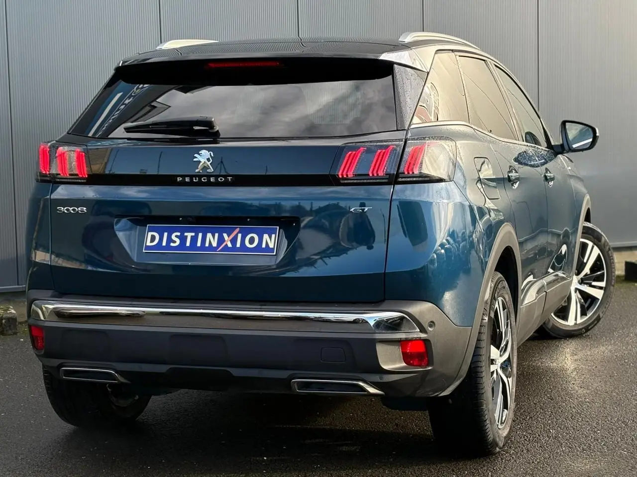 Vue 3/4 arrière droite d'un Peugeot 3008 GT bleu Célèbes avec toit noir et jantes alliage bi-ton.