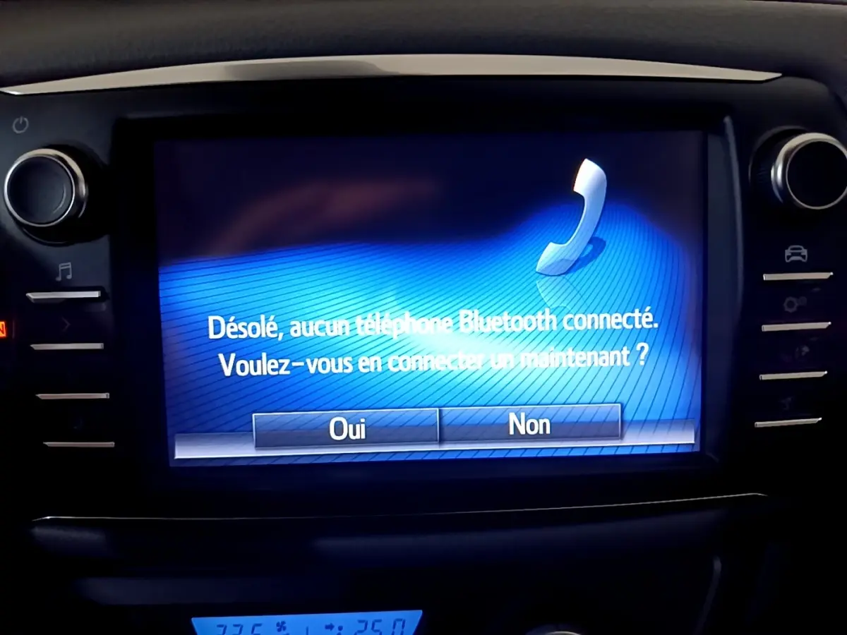 Écran tactile central affichant un message Bluetooth dans l’habitacle d’une Toyota Yaris blanche, vue de face rapprochée.