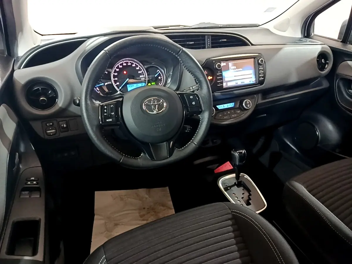Intérieur de la Toyota Yaris 2019 vu de face, volant cuir noir, tableau de bord avec écran tactile et boîte auto.