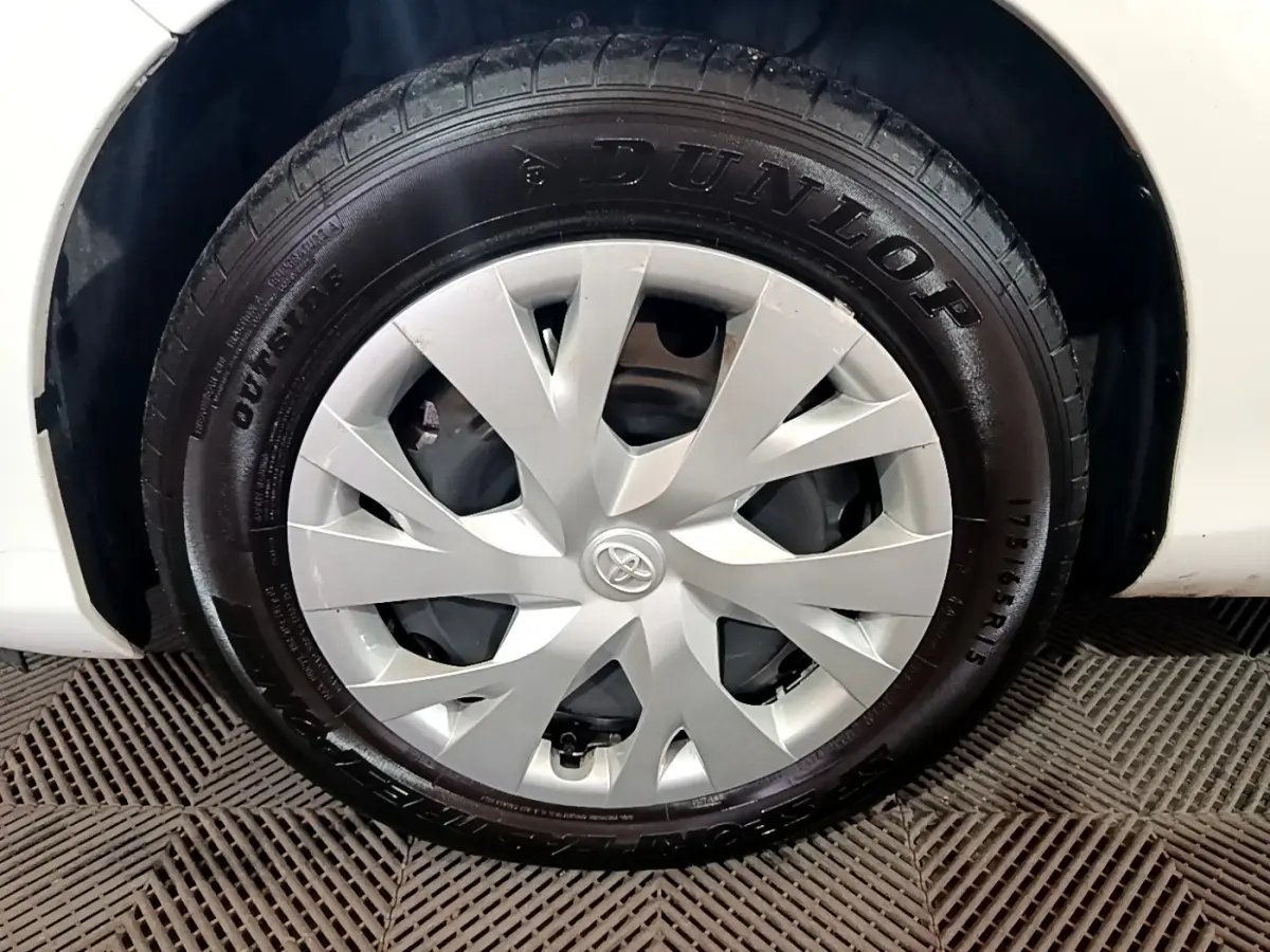 Gros plan sur la roue avant droite blanche d'une Toyota Yaris 1.5 VVT-I HYBRID avec enjoliveur argenté et pneu Dunlop.