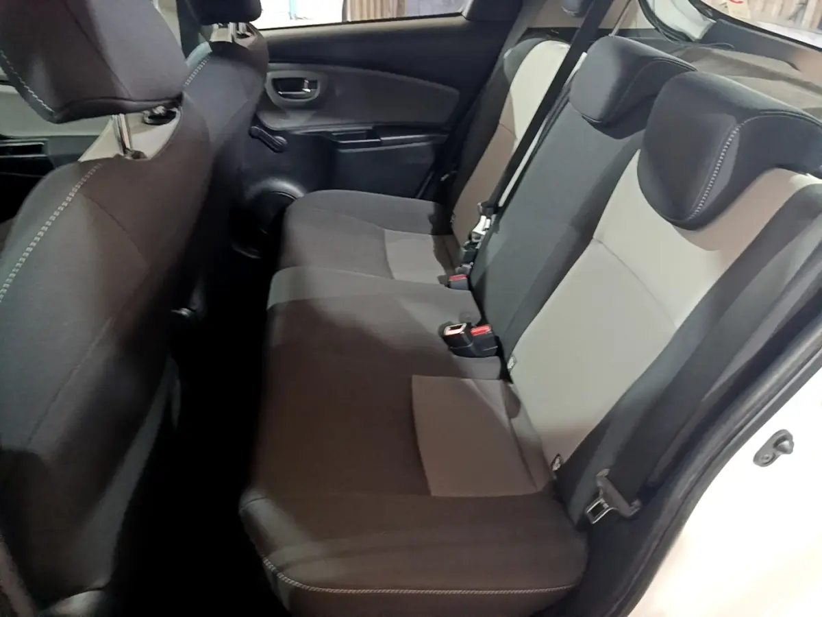 Vue latérale droite sur la banquette arrière bicolore gris clair et foncé de la Toyota Yaris hybride blanche.