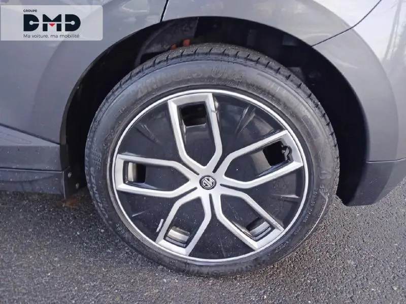 Gros plan sur la roue avant gauche du MG4 EV 204ch Luxury 2023 en Andes Grey métallisé, avec jante au design moderne noir et argent.
