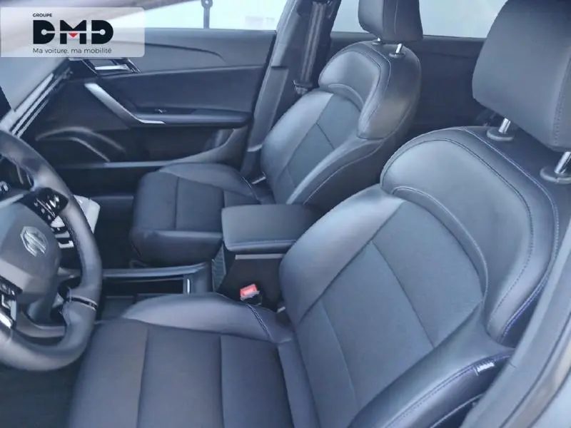 Vue intérieure côté conducteur du MG4 EV 204ch 2023, sièges en cuir noir avec surpiqûres bleues et accoudoir central.